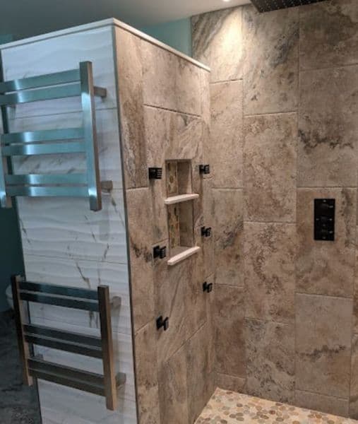 Modern shower design featuring stone tiles, built-in shelves, and a sleek chrome towel warmer.