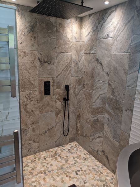Modern bathroom shower with elegant stone walls and a stylish rain showerhead.