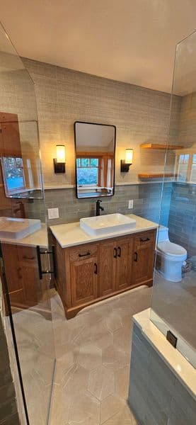 Modern bathroom with glass shower, wooden vanity, and sleek fixtures. Natural light enhances decor.