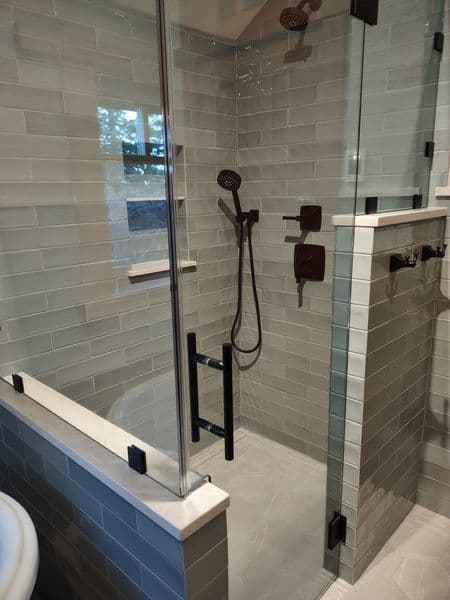 Modern glass shower with gray tiled walls, black fixtures, and elegant design features.