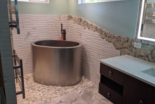 Modern bathroom design featuring a sleek oval bathtub, stone tile flooring, and elegant vanity.