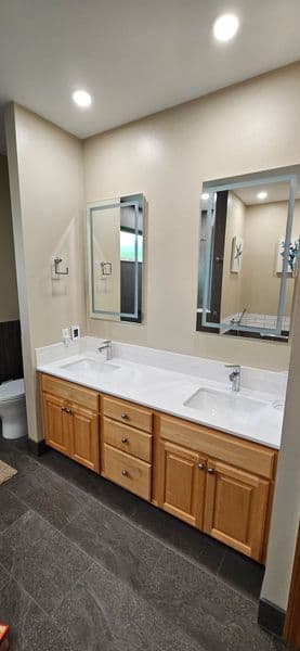 Modern bathroom with double sink vanity, wooden cabinets, and bright lighting.