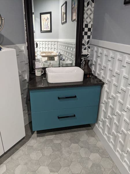 Modern bathroom with turquoise vanity, sleek black countertop, and stylish hexagon tile floor.