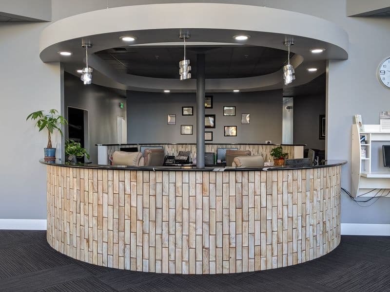 Modern reception desk with wooden paneling in a sleek office lobby setting.